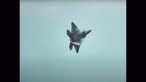 A Fighter Jet Is Flying Through A Clear Blue Sky GIF