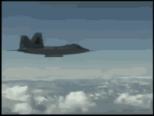 A Fighter Jet Is Flying Through The Clouds With The Letter M On The Tail GIF