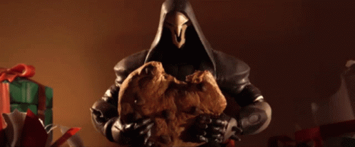 A Figurine Of Reaper Holding A Cookie In Front Of Gifts GIF