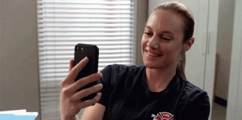 A Firefighter Is Taking A Selfie With Her Cell Phone . GIF