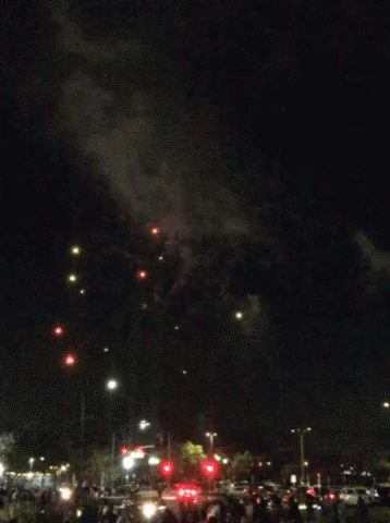 a fireworks display in a parking lot with a crowd watching