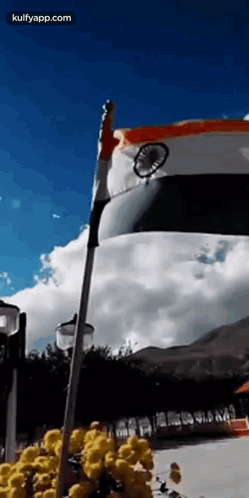 A Flag Is Waving In The Wind In Front Of A Blue Sky . GIF