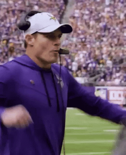 A Football Coach Wearing A Purple Shirt And A White Hat GIF