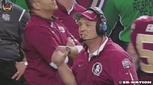 a football coach wearing headphones is giving a thumbs up to his team