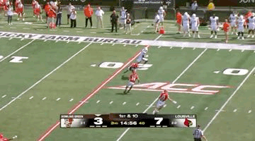 a football game is being played on a field with a scoreboard showing the score .