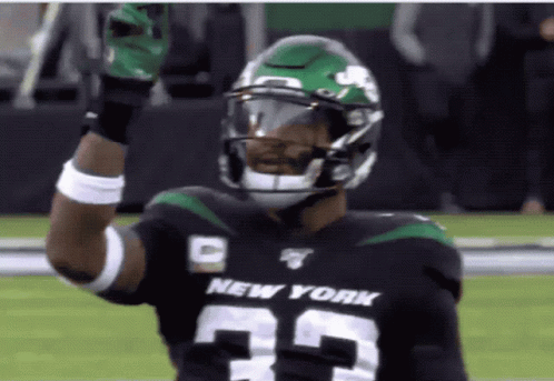 A Football Player For The New York Jets Holds Up His Gloves GIF