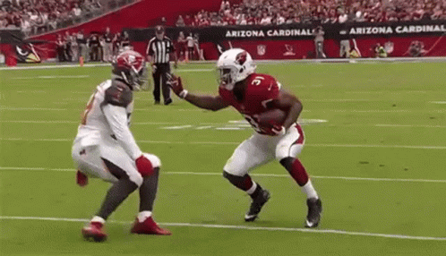 A Football Player From The Arizona Cardinals Is Running With The Ball While Another Player Tries To Stop Him . GIF