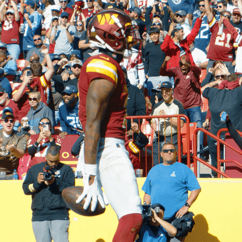 A Football Player Holds A Ball In Front Of A Crowd With The Number 22 On His Shirt GIF
