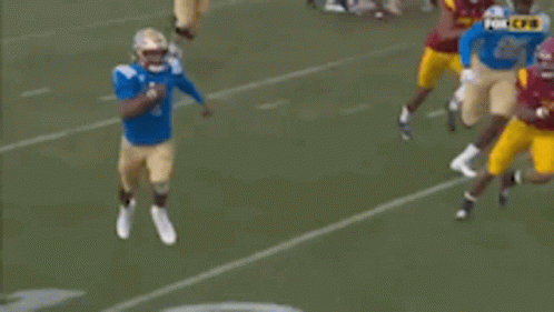 a football player in a blue jersey is running with a ball on a field .