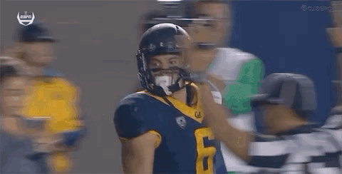 A Football Player In A Helmet Is Being Tackled By Another Player . GIF