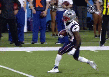 A Football Player In A Patriots Uniform Is Running With The Ball . GIF