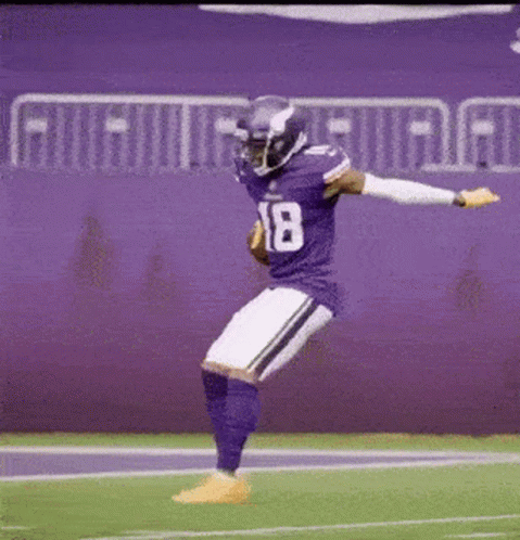 a football player in a purple uniform is jumping in the air on the field .