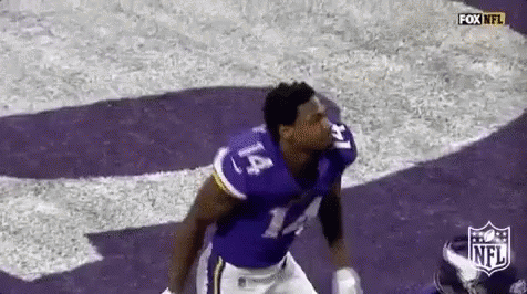 A Football Player In A Purple Uniform Is Running On A Field . GIF