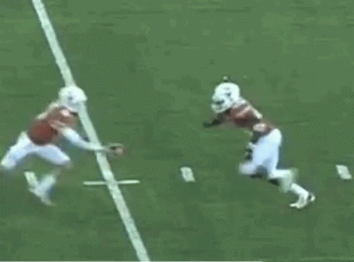 A Football Player In A Red Jersey Is Being Tackled By Another Player In A White Jersey GIF