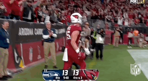 A Football Player In A Red Uniform Is Running On The Field During A Game Against The Seahawks . GIF