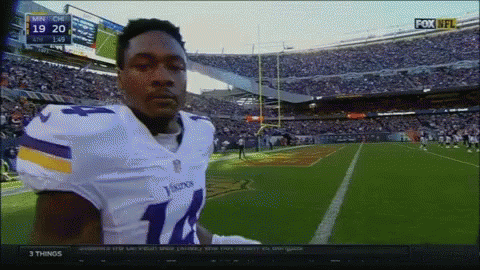 A Football Player In A Vikings Uniform Stands In Front Of A Crowd GIF