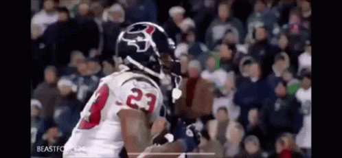 A Football Player In A White Jersey With The Number 23 On It Is Running With The Ball In Front Of A Crowd . GIF