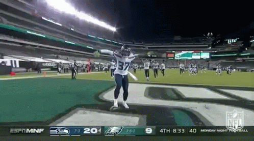 A Football Player Is Jumping In The Air On A Field During A Game GIF