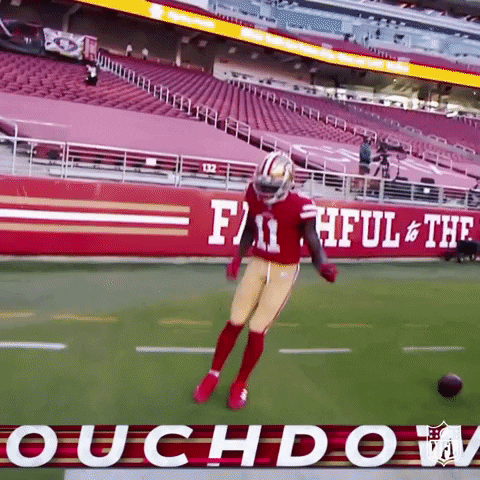 A Football Player Is Jumping In The Air On A Field In Front Of A Sign That Says Faithful & The Roughdown GIF
