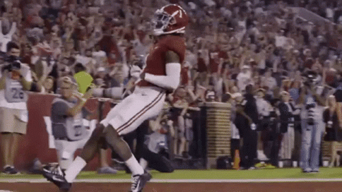 A Football Player Is Jumping In The Air While Catching A Pass On A Field . GIF
