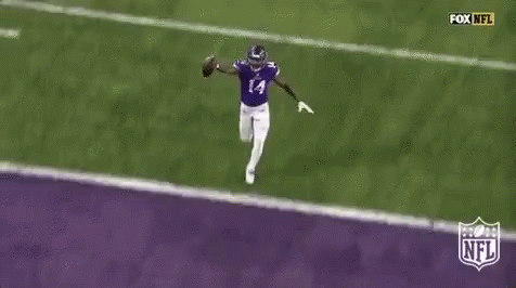 A Football Player Is Running Across A Purple Field With A Ball . GIF