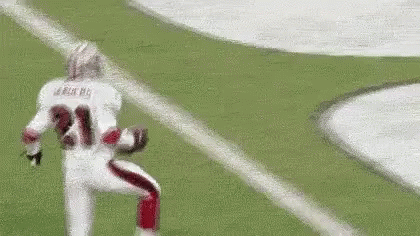 A Football Player Is Running On A Field With A Ball In His Hand . GIF