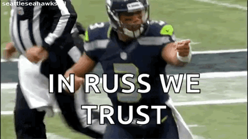 a football player is running on a field with the words `` in russ we trust '' written on the screen .