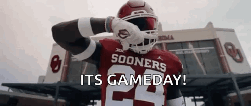 A Football Player Is Standing In Front Of A Stadium With The Words `` Its Gameday '' Written On The Screen . GIF