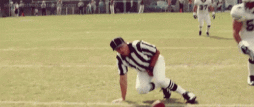 A Football Player Is Throwing A Ball In Front Of A Crowd Of People . GIF