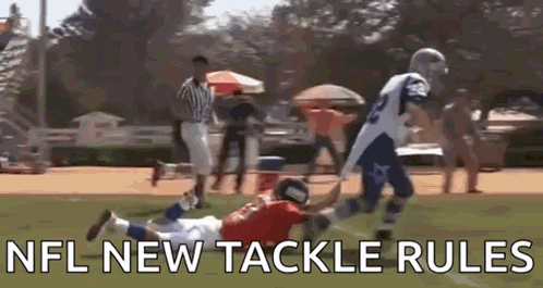 A Football Player Is Trying To Tackle Another Player On A Field While A Referee Watches . GIF