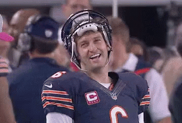 A Football Player Is Wearing A Helmet And Smiling While Standing On The Field . GIF