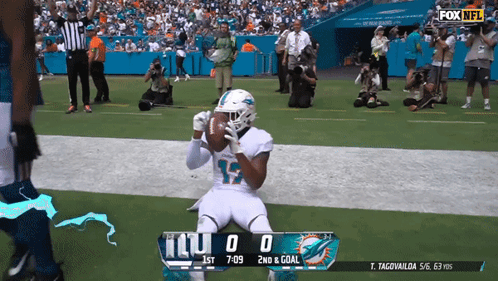 A Football Player Kneeling On The Field With A Scoreboard That Says Miami Dolphins 0 2Nd & Goal GIF