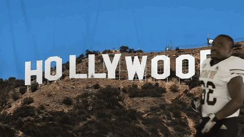 a football player stands in front of a hollywood sign