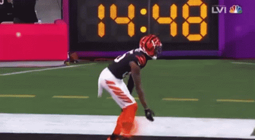 a football player stands on the field in front of a digital scoreboard that says 14:48