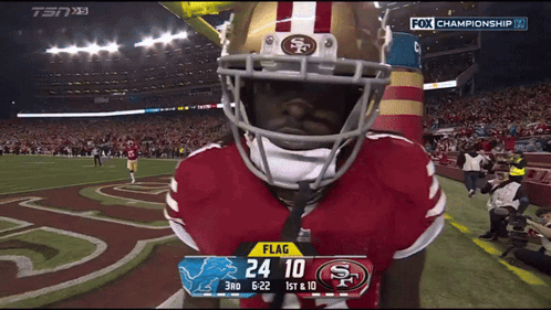 A Football Player Wearing A 49Ers Helmet Stands In Front Of A Scoreboard GIF