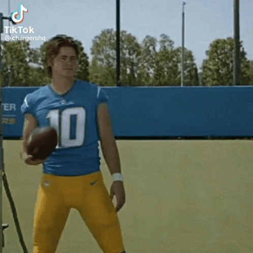 A Football Player Wearing A Blue And Yellow Uniform Is Holding A Football . GIF