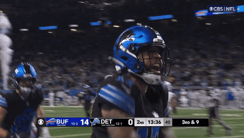 a football player wearing a blue helmet stands on the field