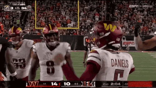 A Football Player Wearing A Daniels Jersey Is Standing On The Field With His Teammates GIF