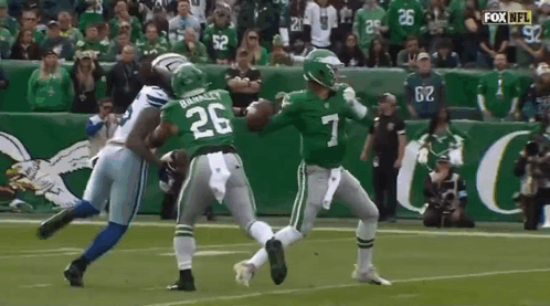 A Football Player Wearing A Green Jersey With The Number 7 On It Is Being Tackled By Another Player . GIF