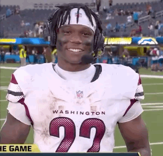 A Football Player Wearing A Headband And Headphones Is Standing On A Field . GIF