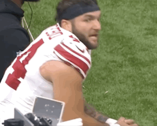 a football player wearing a headband is sitting on the sidelines .