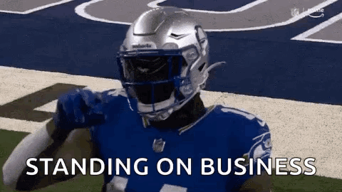 A Football Player Wearing A Helmet Is Standing On A Field With The Words `` Standing On Business '' . GIF
