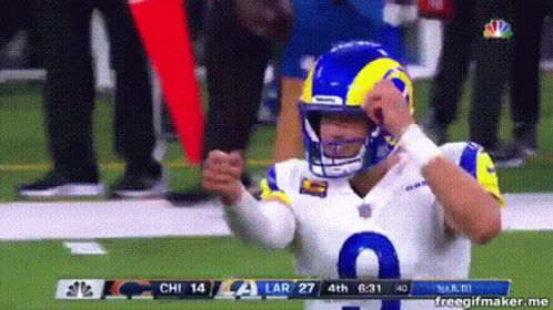 A Football Player Wearing A Helmet Is Standing On The Field . GIF