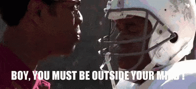 A Football Player Wearing A Helmet Is Talking To Another Man . GIF