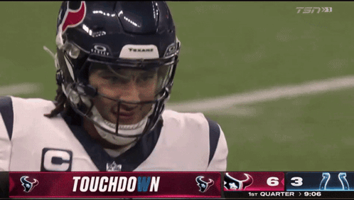 A Football Player Wearing A Helmet Stands In Front Of A Touchdown Screen GIF