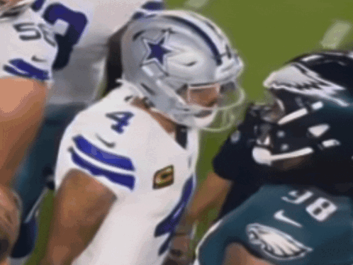 A Football Player Wearing A Helmet With A Star On It Is Talking To Another Player . GIF
