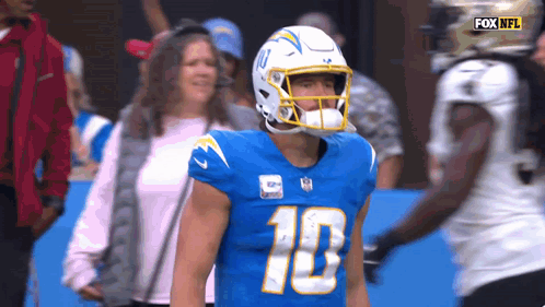 A Football Player Wearing A Helmet With The Number 10 On It Stands On The Field . GIF