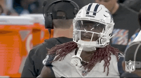 A Football Player Wearing A Helmet With The Word Cowboys On It Is Talking To A Referee . GIF