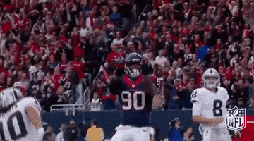 A Football Player Wearing A Jersey With The Number 90 On It Is Running In Front Of A Crowd During A Game . GIF