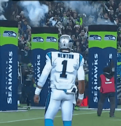 A Football Player Wearing A Number 1 Jersey Stands In Front Of Seahawks Banners GIF